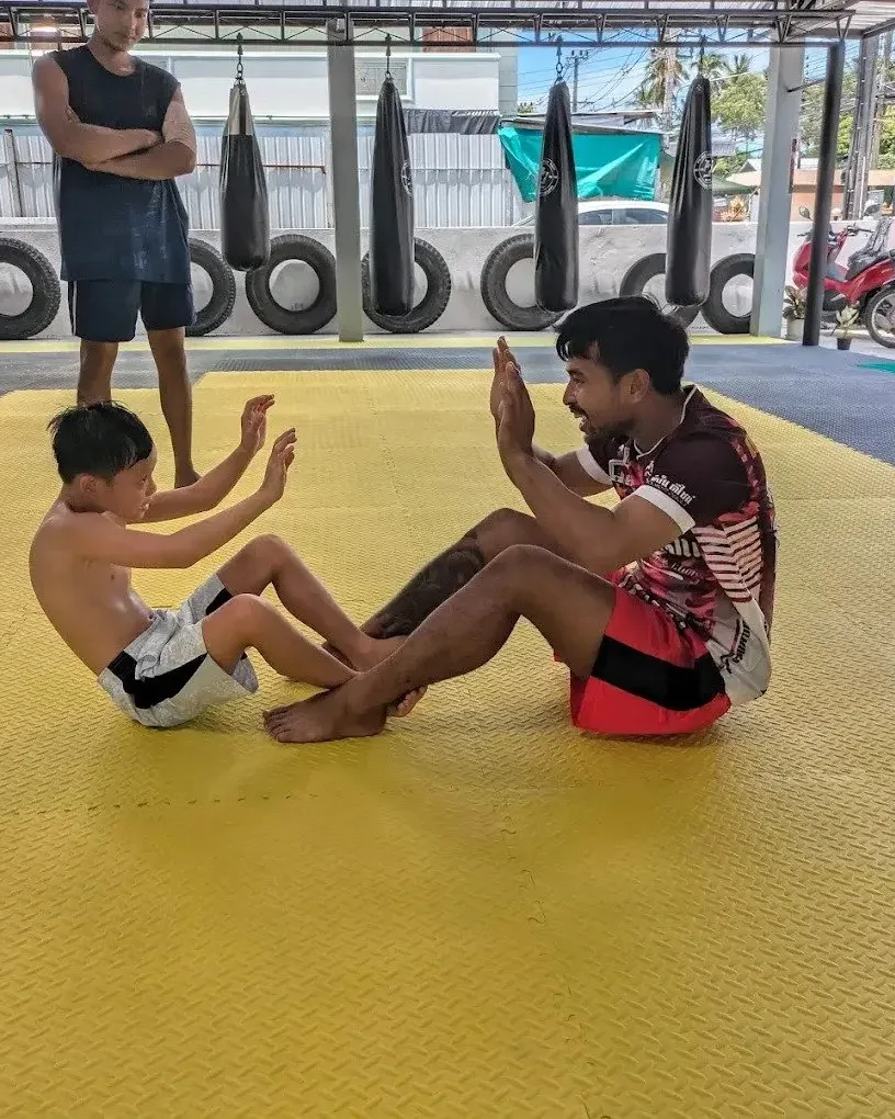 Coach leading kids crunches on the mat at PM PAYU, Koh Samui