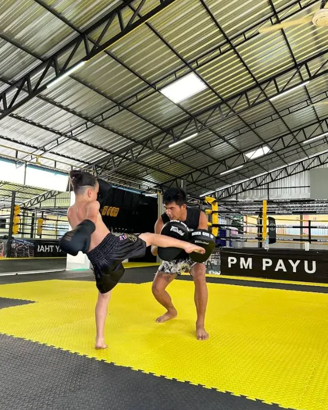Kru Payu holding pads with a kid at PM PAYU Muaythai, Koh Samui