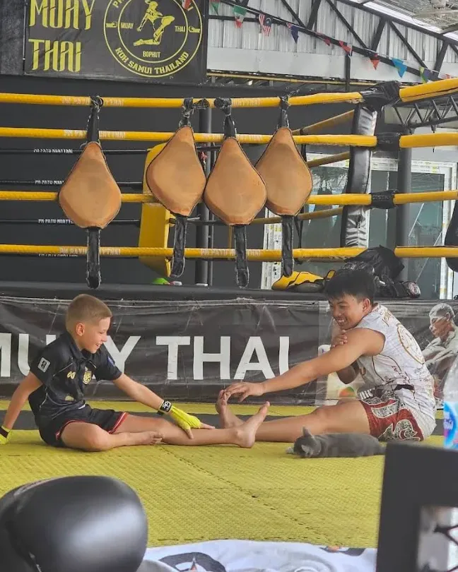 Kru Petch stretching with a kid at PM PAYU Muaythai, Koh Samui