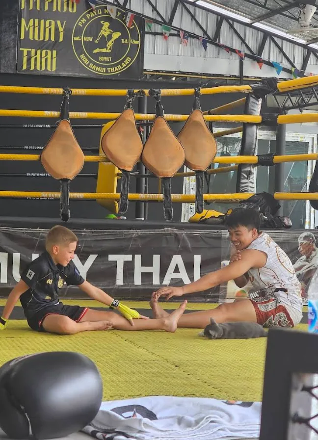 Kru Petch stretching with a kid at PM PAYU Muay Thai, Koh Samui