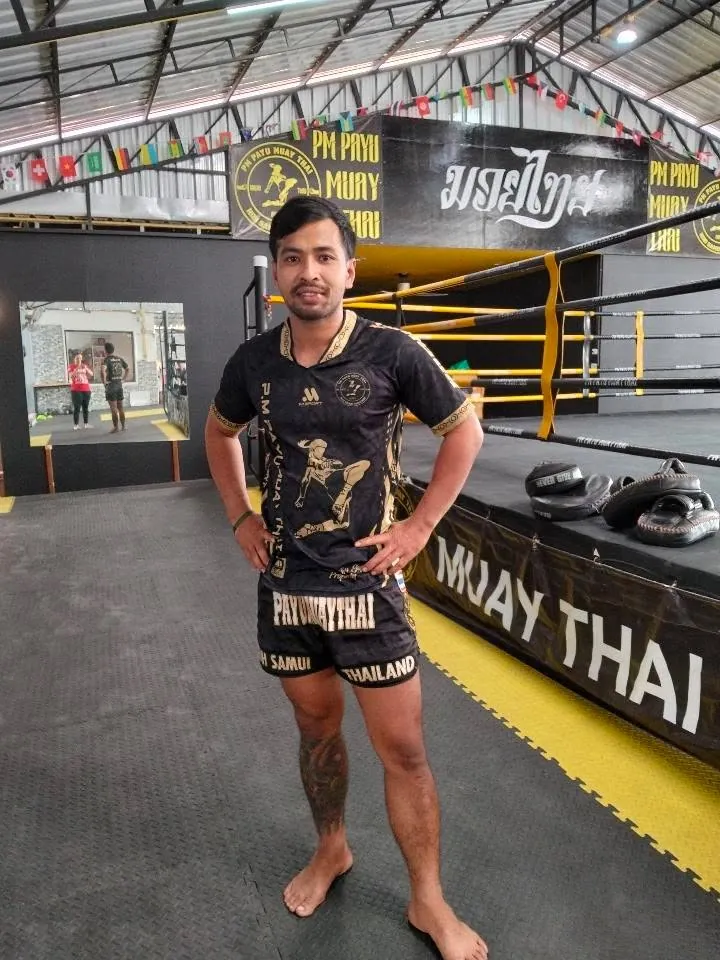 Kru Kong smiling with fists raised at PM PAYU Muay Thai, Koh Samui